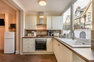 a kitchen with white cabinets and a large window at Austin Terrace in Gorleston-on-Sea