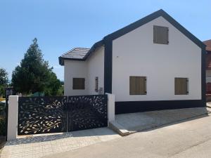 uma casa branca com um portão preto e branco em Zánka Villa em Zánka