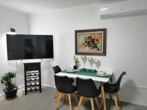 comedor con mesa, sillas y TV en Centre Takapuna 2 Beds & Garage & Netflix, en Auckland