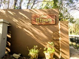 una señal en el costado de una pared con plantas en Cabañas El Francés en Merlo