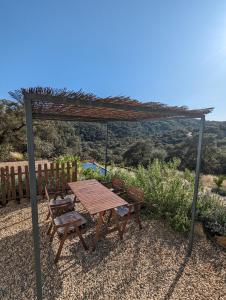 una mesa de picnic de madera y sillas bajo una pérgola en Finca Bravo, en Cortegana