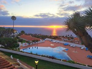 Sunny Tenerife Apartment - ocean views في تاكورونتي: اطلالة منتجع مع مسبح وغروب الشمس