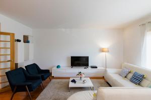 a living room with a white couch and two blue chairs at Garden Mills Apartment in Lisbon
