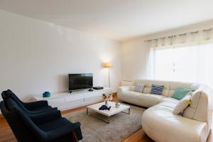 a white living room with a white couch and a tv at Garden Mills Apartment in Lisbon