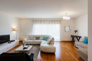 a living room with a white couch and a tv at Garden Mills Apartment in Lisbon