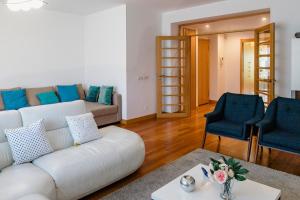 een woonkamer met een witte bank en 2 blauwe stoelen bij Garden Mills Apartment in Lissabon