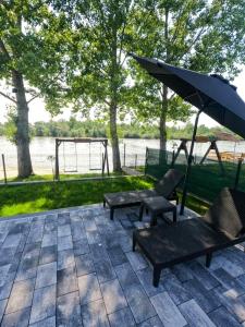 a patio with two chairs and an umbrella and a swing at Drinska Prica - Vikendica na Drini in Loznica +38 photos