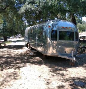 un vecchio furgone argentato parcheggiato sotto un albero. di Oak Knoll Village a Palomar Mountain