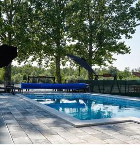 a swimming pool with a blue pool table and umbrellas at Drinska Prica - Vikendica na Drini in Loznica