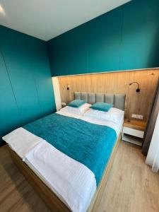 a bedroom with a large bed with a blue wall at Apartament Fredry 2 PREMIUM KLIMA in Kołobrzeg
