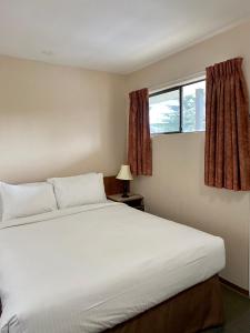 een slaapkamer met een groot wit bed en een raam bij Sea Edge Motel in Parksville