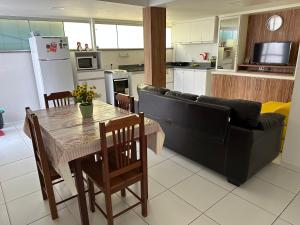 a kitchen and living room with a table and a couch at Apto 2 Quartos Perfeito in Guarapari