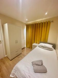 um quarto com uma cama branca e cortinas amarelas em 2BR Flat near Central Southall em Southall