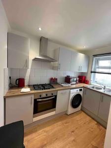 a kitchen with white cabinets and a stove and a dishwasher at 2BR Flat near Central Southall in Southall