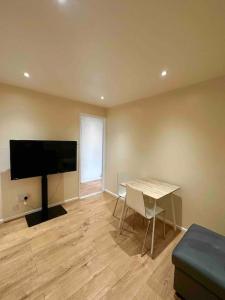 uma sala de estar com uma mesa e uma televisão de ecrã plano em 2BR Flat near Central Southall em Southall
