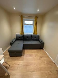 uma sala de estar com um sofá preto e uma janela em 2BR Flat near Central Southall em Southall