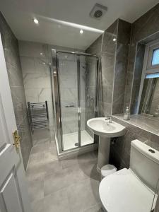 uma casa de banho com um chuveiro, um WC e um lavatório. em 2BR Flat near Central Southall em Southall