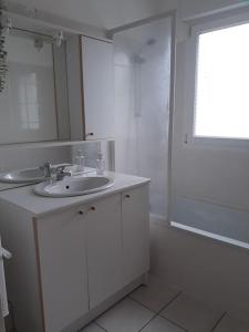 La salle de bains blanche est pourvue d'un lavabo et d'un miroir. dans l'établissement Appartement au RDC avec jardin clos, au calme., à Saint-Aubin-du-Cormier