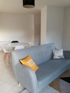 - un canapé bleu dans le salon avec une table dans l'établissement Appartement au RDC avec jardin clos, au calme., à Saint-Aubin-du-Cormier