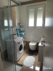 a bathroom with a washing machine and a toilet at Apartments Bouvier in Pag