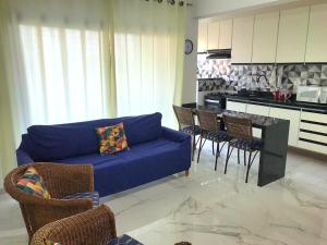 a living room with a blue couch and a kitchen at Capitânia Varam in Guarujá