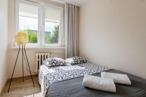 1 dormitorio con cama con almohadas y ventana en INITIUM rooms - Apartament - Tysiąclecia 23B en Gdansk