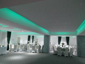 a banquet hall with white tables and chairs and green lighting at Popasul lui Gicuță in Curtea de Argeş