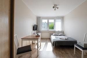 a bedroom with a bed and a desk and a window at INITIUM rooms - Apartament - Tysiąclecia 23B in Gdańsk