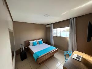 um quarto com uma cama, uma secretária e uma janela em Dok Brasília Hotel Unidade Águas Claras em Taguatinga