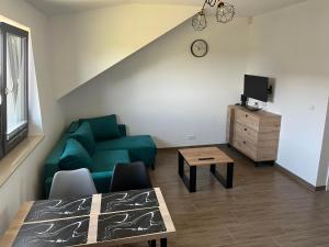 uma sala de estar com um sofá verde e uma mesa em Apartamenty Pod Jodłami em Sarbinowo