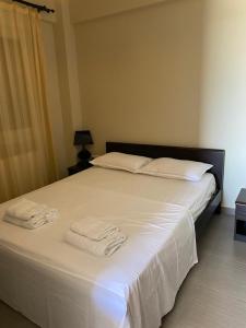 a bedroom with a large white bed with towels on it at Vasilia in Nea Irakleia