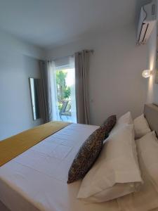 a bedroom with a large white bed with a window at Coritos holiday apartments in Kontokali