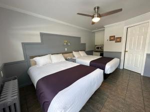 a bedroom with two beds and a ceiling fan at Motel Le Refuge in Sherbrooke