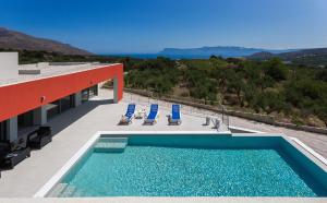 a swimming pool on the side of a building with blue chairs at Gramvousa Villas in Kissamos