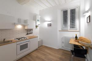 eine Küche mit weißen Geräten und einem Holztisch in der Unterkunft PINTURICCHIO Guest House in Perugia
