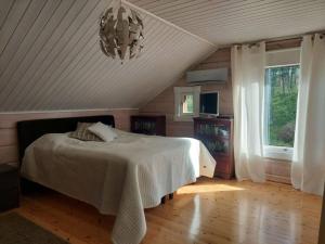 1 dormitorio con cama y lámpara de araña en Villa Mustalahti en Mikkeli