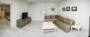 a living room with a couch and a tv at Reshkov Pool Apartments in Gevgelija