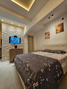 - une chambre avec un grand lit et un mur en pierre dans l'établissement Studio apartmani Vukasin, à Tivat