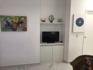 a living room with a tv on a white wall at Capitânia Varam in Guarujá