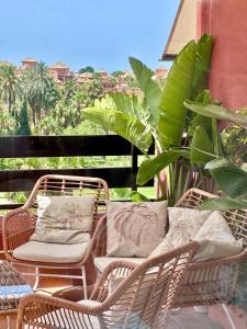 a balcony with wicker chairs and tables and a plant at Playa Granada Golf Apartamentos in Motril