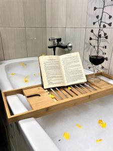 un libro sobre una bandeja en la bañera con una copa de vino en Luxury Wide View Apartment Pohorje Bellevue en Hočko Pohorje