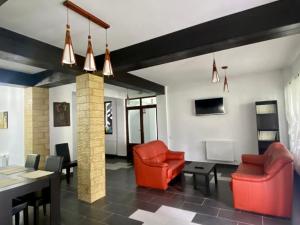 a living room with two red chairs and a table at Pensiunea Cassandra in Neagra Şarului