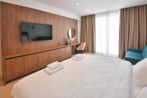 a hotel room with a large white bed and a television at Luxury Hotel Riva - Budva in Budva