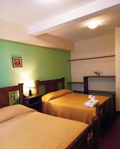 2 camas en una habitación de hotel con paredes verdes en Hotel Maison Fiori Prado, en Cochabamba