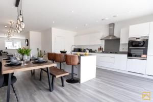 a kitchen and dining room with white cabinets and a table at Outstanding 5 Bedroom Townhouse, Canal Views By Valore Property Services in Milton Keynes