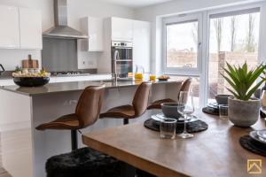 a kitchen with a wooden table with leather chairs at Outstanding 5 Bedroom Townhouse, Canal Views By Valore Property Services in Milton Keynes