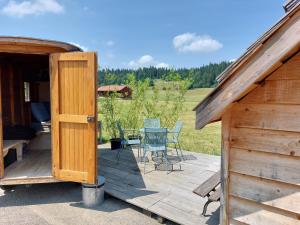 a wooden deck with a table and chairs on it at Drosera cabane et roulotte in La Chaux-du-Milieu