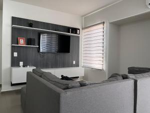 Una sala de estar con un sofá y un televisor. en BONITO DEPA ! Cerritos a 2 Cuadras de PLAYA, en La Florida