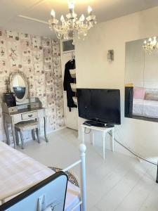 een woonkamer met een televisie en een tafel met een spiegel bij Happy Place with kitchenette- female only in Sydenham