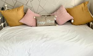 Una cama con un montón de almohadas. en Happy Place with kitchenette- female only, en Sydenham